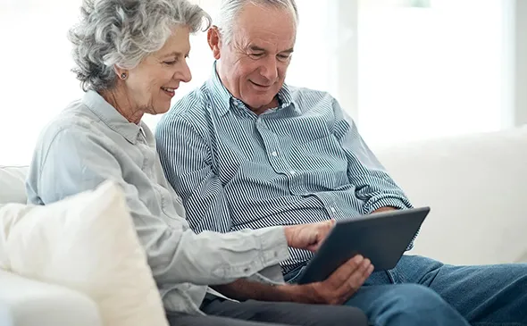 Senior couple reviewing finances on a tablet, ensuring lifetime income with confidence through annuities in San Marcos, TX.